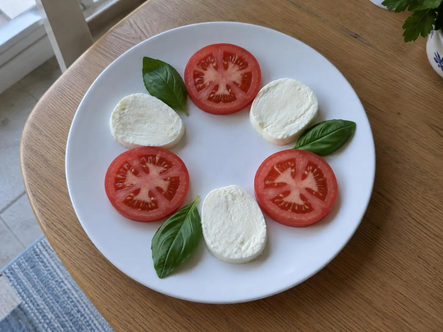AI-made sample phone photo of a caprese salad of three tomato and three mozzarella slices with three basil leaves; generated demonstration, not a real customer dish.